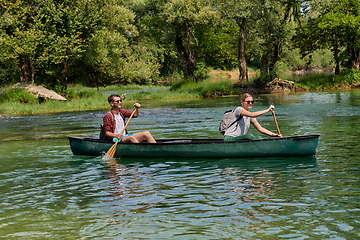 Image showing friends are canoeing in a wild river