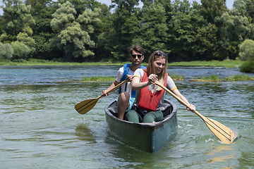 Image showing friends are canoeing in a wild river