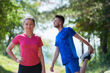 Image showing couple enjoying in a healthy lifestyle warming up and stretching before jogging