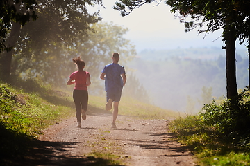 Image showing couple enjoying in a healthy lifestyle while jogging on a country road