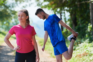 Image showing couple enjoying in a healthy lifestyle warming up and stretching before jogging