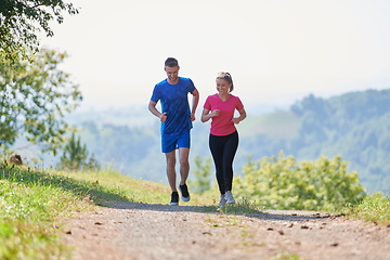 Image showing couple enjoying in a healthy lifestyle while jogging on a country road