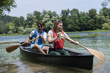 Image showing friends are canoeing in a wild river