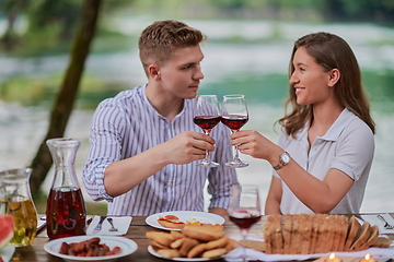 Image showing couple toasting red wine glass while having picnic french dinner party outdoor