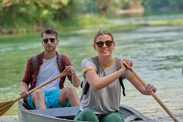 Image showing friends are canoeing in a wild river