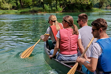 Image showing Group adventurous explorer friends are canoeing in a wild river