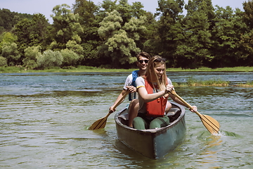 Image showing friends are canoeing in a wild river