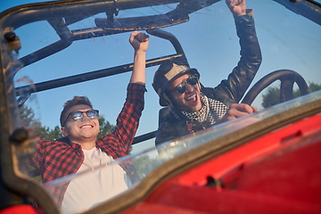 Image showing two young happy excited men enjoying beautiful sunny day while driving a off road buggy car