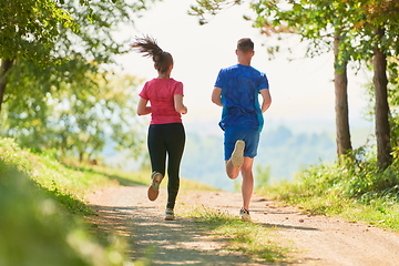 Image showing couple enjoying in a healthy lifestyle while jogging on a country road