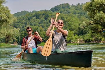 Image showing friends are canoeing in a wild river