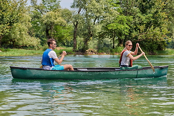 Image showing friends are canoeing in a wild river