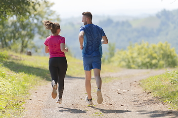 Image showing couple enjoying in a healthy lifestyle while jogging on a country road