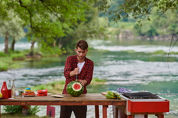 Image showing man cutting juicy watermelon during outdoor french dinner party