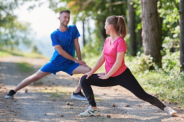 Image showing couple enjoying in a healthy lifestyle warming up and stretching before jogging