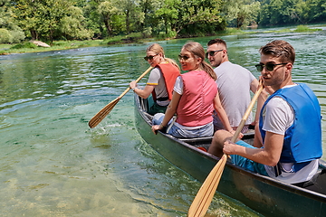 Image showing Group adventurous explorer friends are canoeing in a wild river