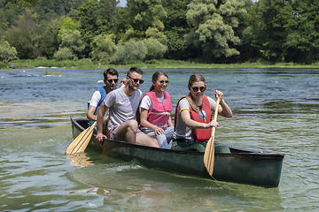 Image showing Group adventurous explorer friends are canoeing in a wild river