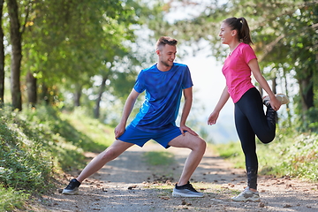 Image showing couple enjoying in a healthy lifestyle warming up and stretching before jogging