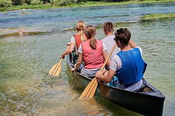 Image showing Group adventurous explorer friends are canoeing in a wild river