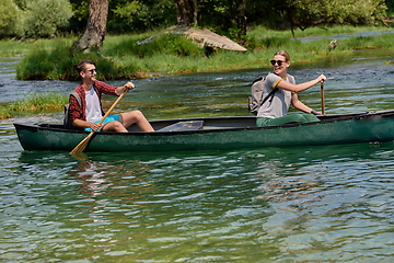 Image showing friends are canoeing in a wild river