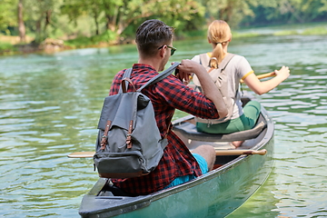 Image showing friends are canoeing in a wild river