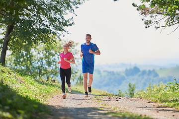 Image showing couple enjoying in a healthy lifestyle while jogging on a country road