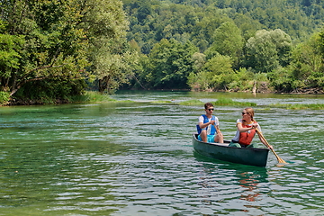 Image showing friends are canoeing in a wild river