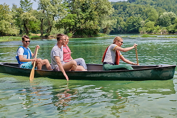 Image showing Group adventurous explorer friends are canoeing in a wild river