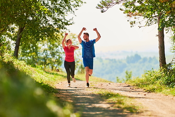 Image showing couple enjoying in a healthy lifestyle while jogging on a country road