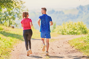 Image showing couple enjoying in a healthy lifestyle while jogging on a country road