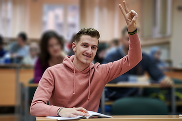 Image showing The student raises his hands asking a question in class in college