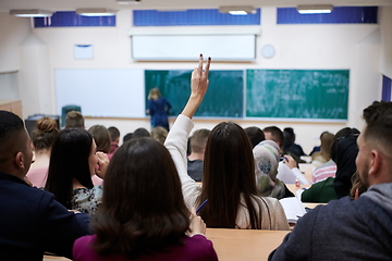 Image showing female student sitting in the class and raising hand up