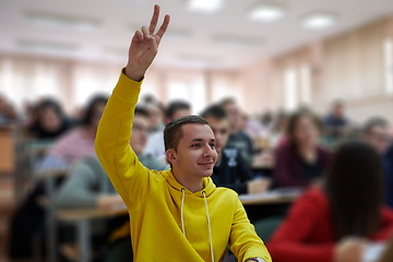 Image showing The student raises his hands asking a question in class in college