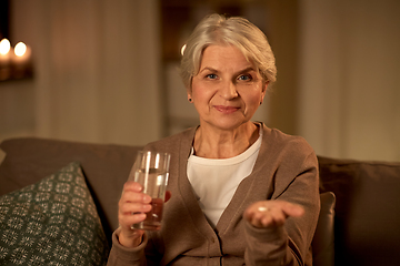 Image showing senior woman with water and medicine at home