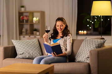 Image showing young woman reading book and drinking wine at home