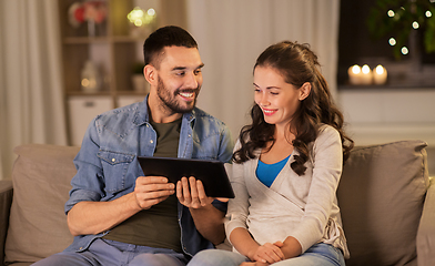 Image showing happy couple using tablet pc at home in evening