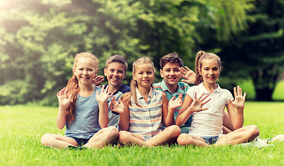 Image showing group of happy kids waving hands outdoors