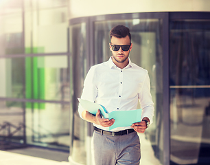 Image showing young man with business file on city street