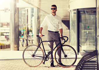 Image showing young man parking his bicycle on city street