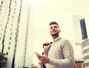 Image showing happy young man with bag and smartphone in city