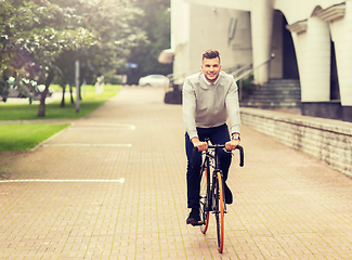 Image showing young man riding bicycle on city street