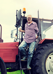 Image showing old man or farmer getting out of tractor at farm