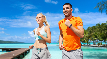 Image showing smiling couple running along exotic on beach