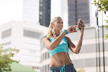 Image showing happy woman with smartphone and earphones at city