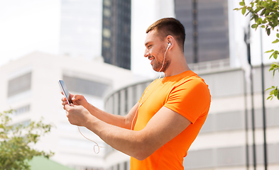 Image showing smiling young man with smartphone and earphones