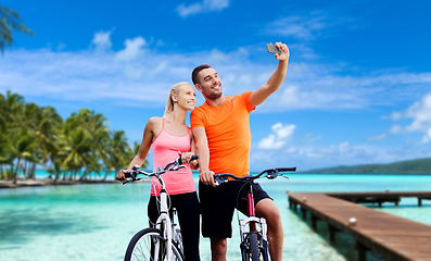 Image showing couple with bicycles taking selfie by smartphone