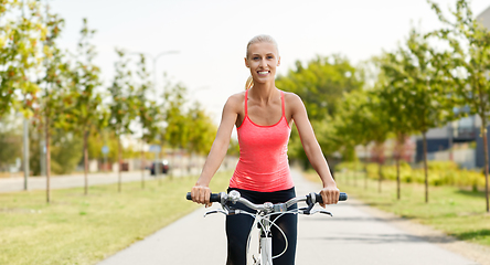 Image showing happy young woman riding bicycle outdoors