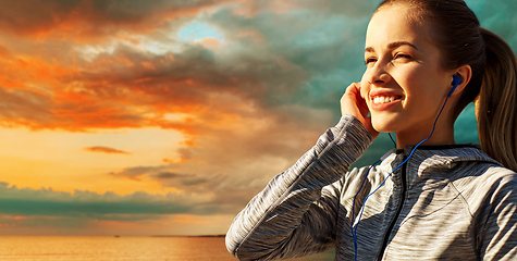 Image showing happy couple with earphones running over sea