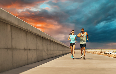 Image showing couple in sports clothes running along pier