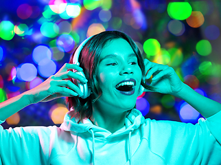 Image showing woman in headphones listening to music over lights