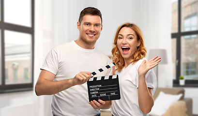 Image showing happy couple in white t-shirts with clapperboard